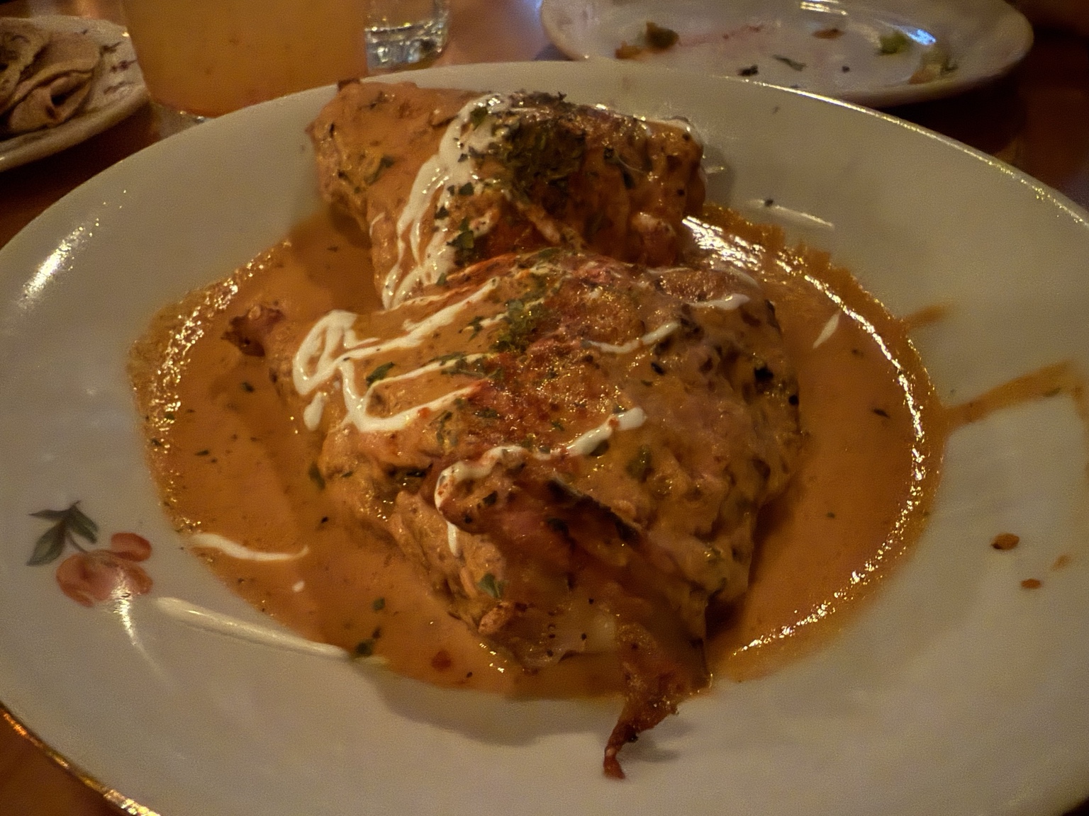 A plated dish in orange sauce with a white drizzle and herbs at Kundah Hôtel in Quebec City
