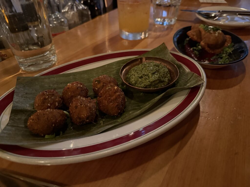 Golden fried snacks served on a leaf with green sauce at Kundah Hôtel in Quebec City