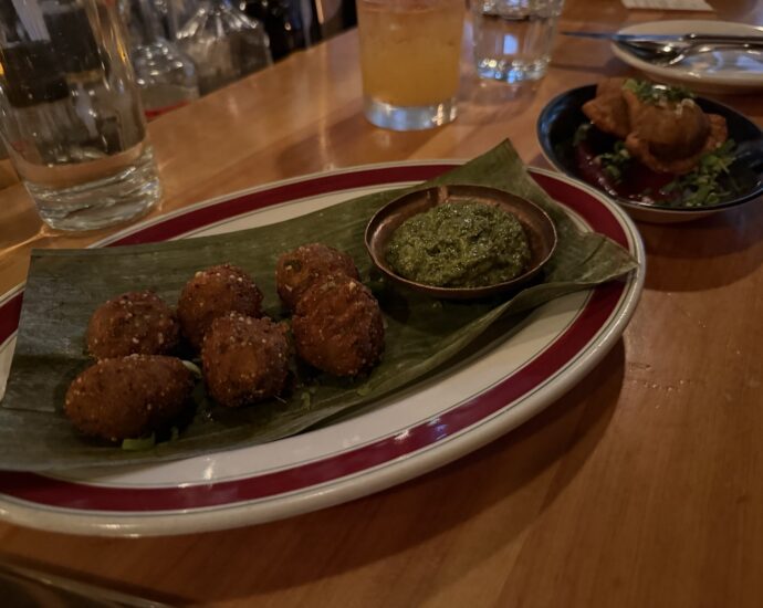 Golden fried snacks served on a leaf with green sauce at Kundah Hôtel in Quebec City
