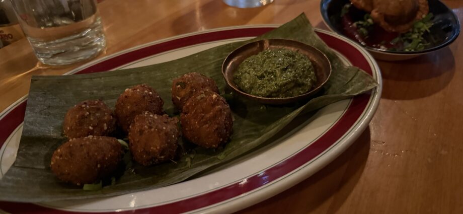 Golden fried snacks served on a leaf with green sauce at Kundah Hôtel in Quebec City
