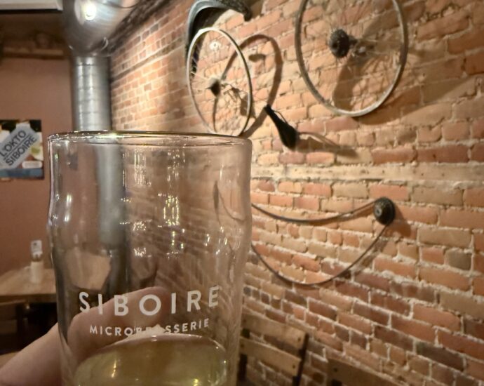 A Siboire glass in front of bicycle wheels and tires decorating a brick wall inside Siboire Saint-Vallier